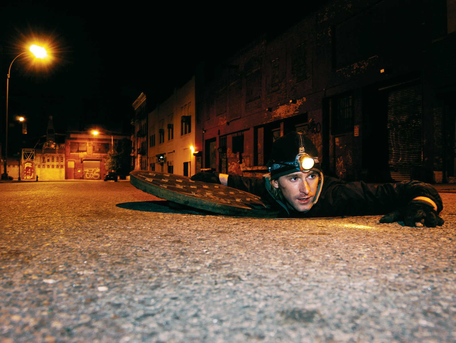 Photographer Steve Duncan crawling out of a man hole