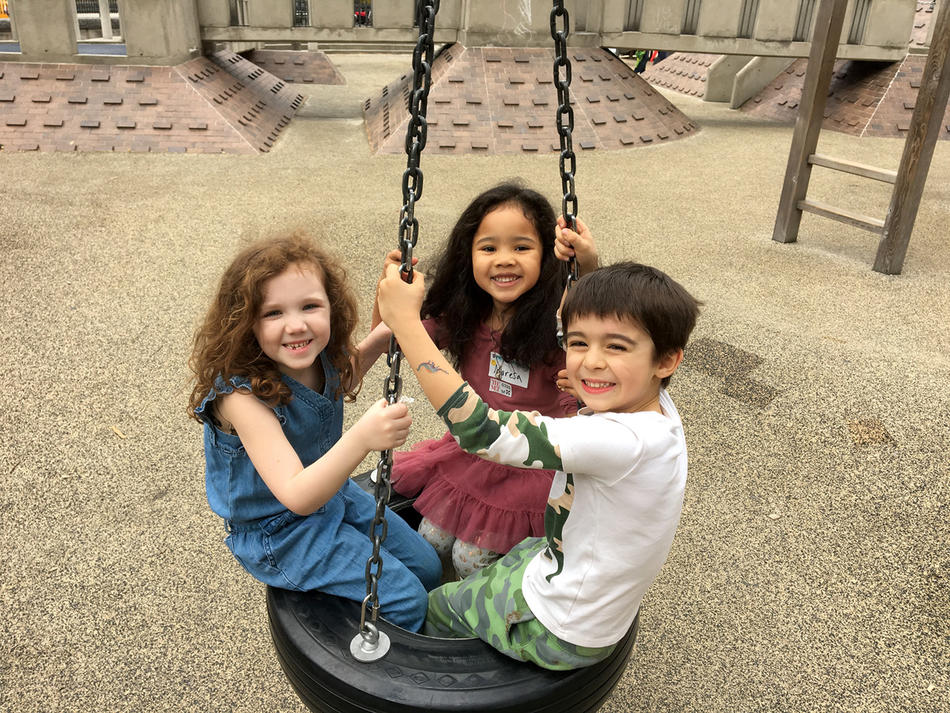 Three children on a tire swing