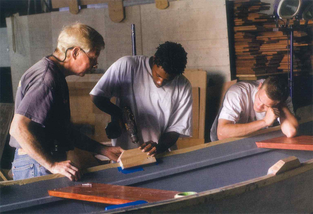 People building a boat in a workshop, photographed by Vernon Doucette