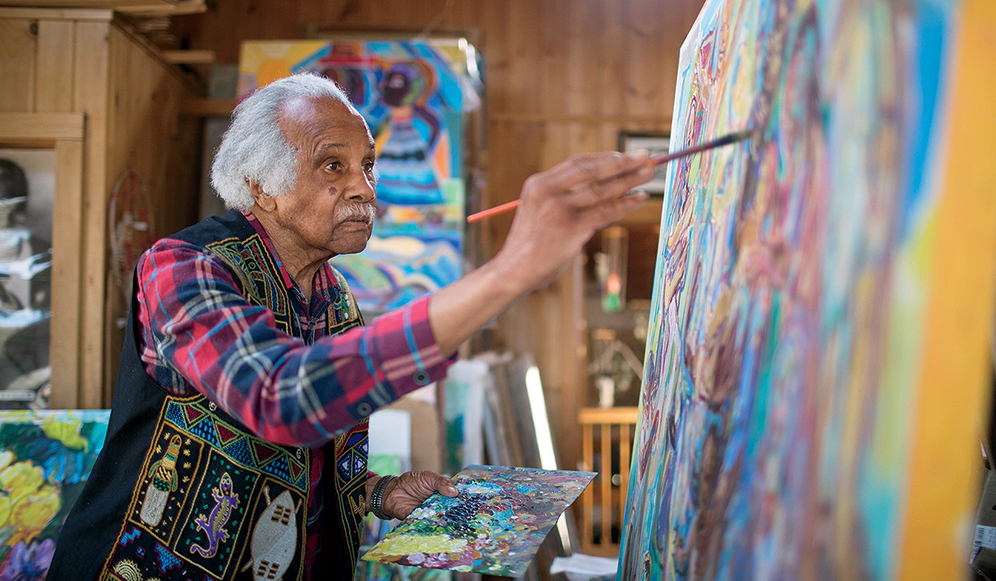 Ashley Bryan painting in his studio, photographed by Matt Cosby