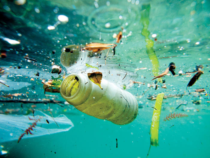 Underwater photo of plastic bottle and other trash floating in ocean