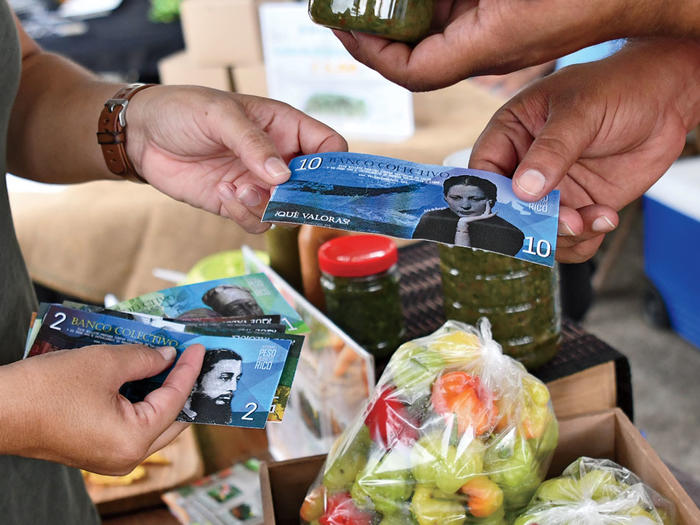 People exchanging "Pesos of Puerto Rico" as part of Columbia professor Frances Negrón-Muntaner's "Valor y Cambio" project 