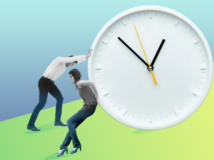 two people pushing a clock up a hill 