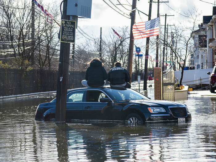 People sitting on a car during a flood