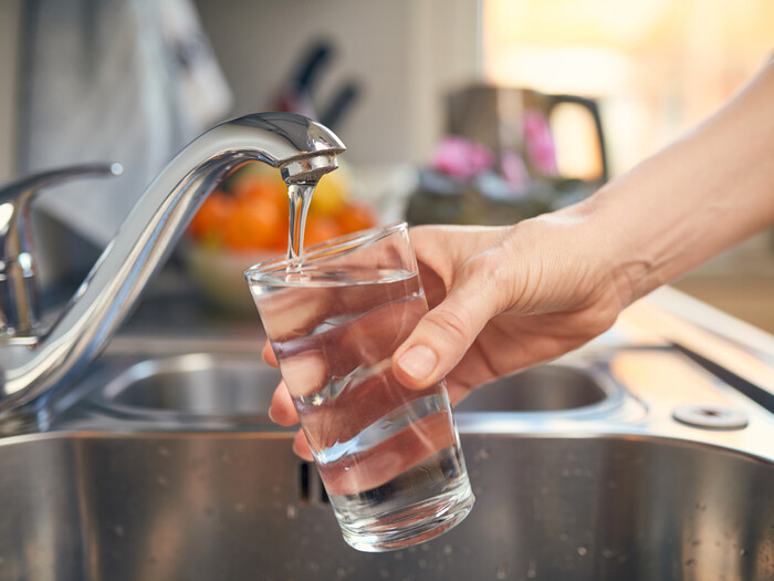 Hand filling up glass from water tap