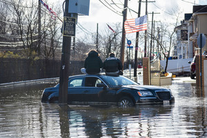 People sitting on a car during a flood