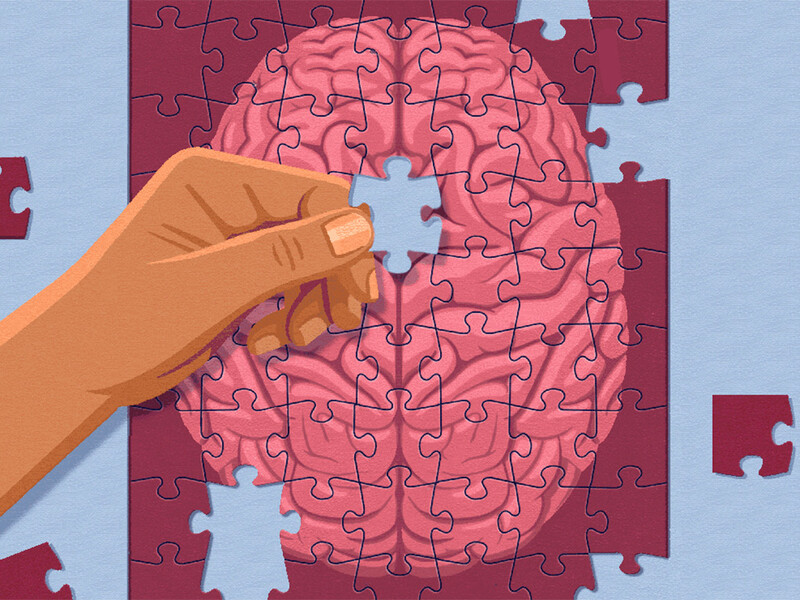 Hand placing puzzle piece on puzzle of a brain