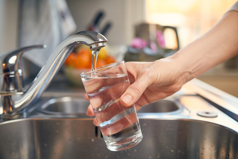 Hand filling up glass from water tap
