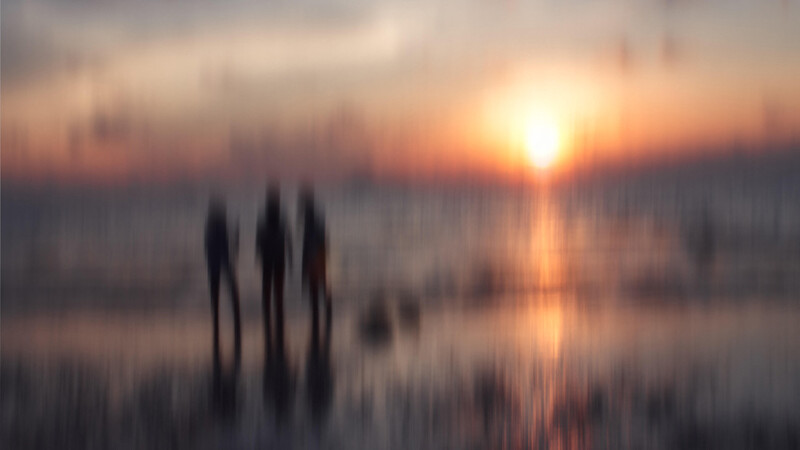 hazy photo of three figures on a beach