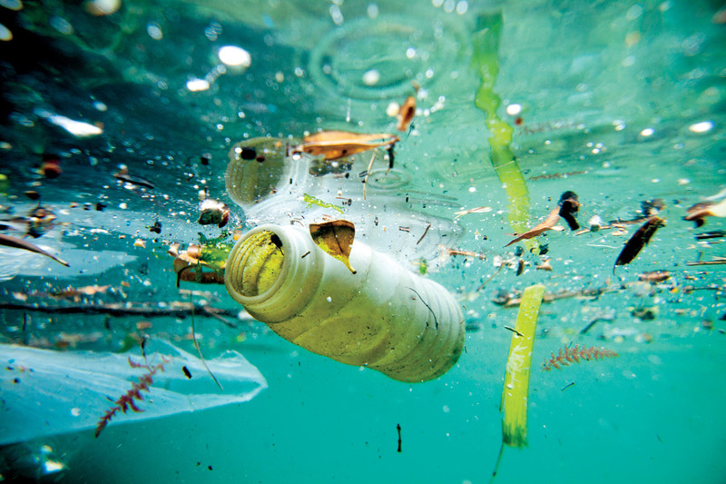 Underwater photo of plastic bottle and other trash floating in ocean