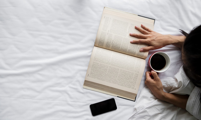 Photo of a person reading while drinking coffee