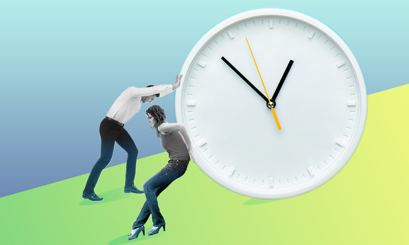 two people pushing a clock up a hill 