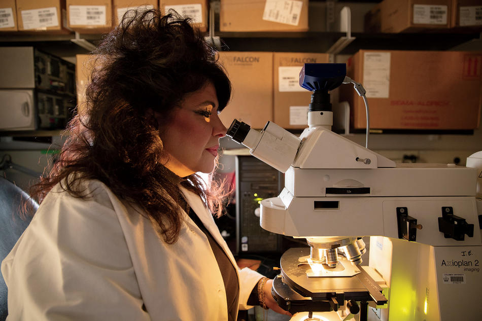 Geneticist Angela Christiano looking through a microscope in her research lab at Columbia University Irving Medical Center
