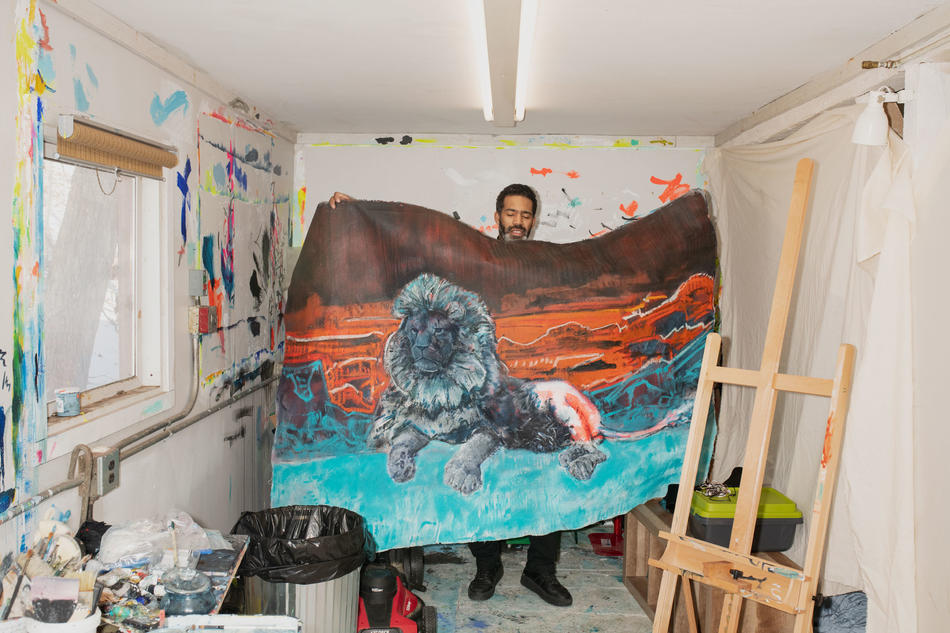 Cy Gavin in his studio holding up his painting of a lion