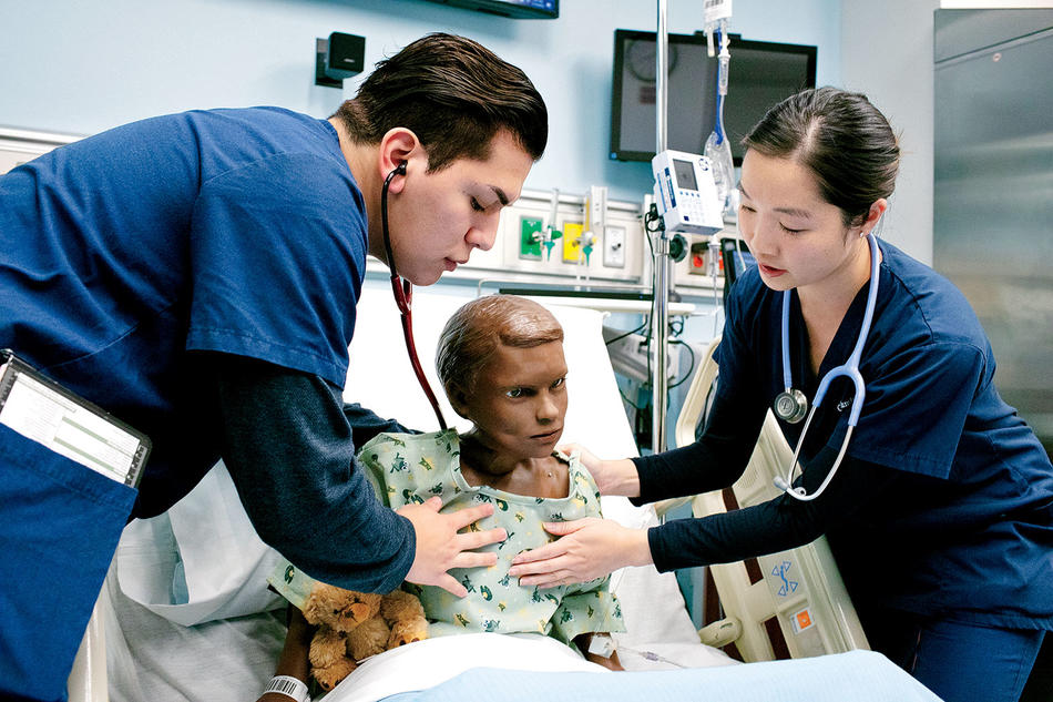 Chris Bustamante and Katie Chen, both master’s degree students, listen for signs of lung congestion in the patient simulation robot.