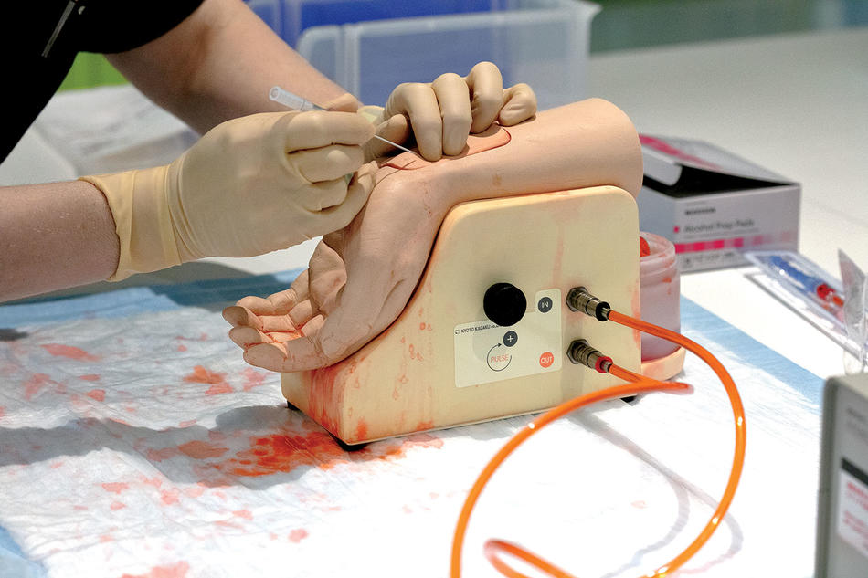 A synthetic wrist with fake blood pulsing through a plastic artery helps students perfect their needle skills.