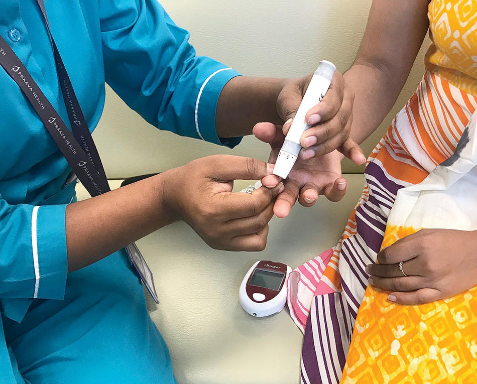 A Praava Health nurse tests a patient’s blood during a home visit