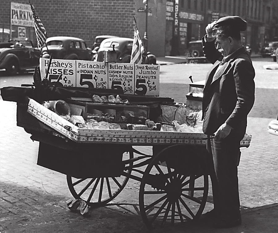 Photo by Rebecca Lepkoff of a man in the Lower East Side standing next to a cart selling nuts and candy on the street