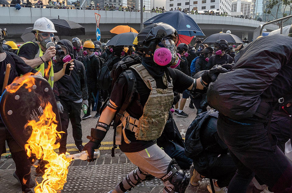 Hong Kong: An anti-government protester throws a Molotov cocktail at riot police. Photograph by Bing Guan, fall 2019