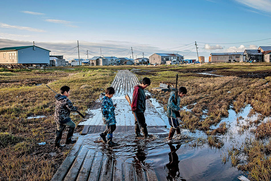 Yupik boys cross a flooded walkway in Alaska, photographed by Katie Orlinsky