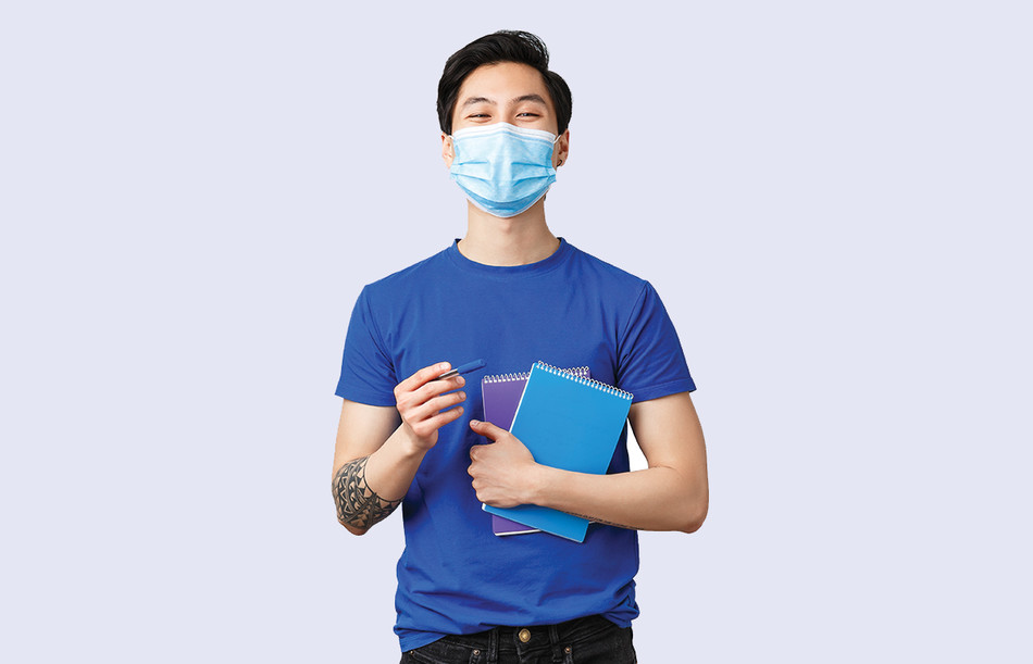 A college student holding books and wearing a face mask