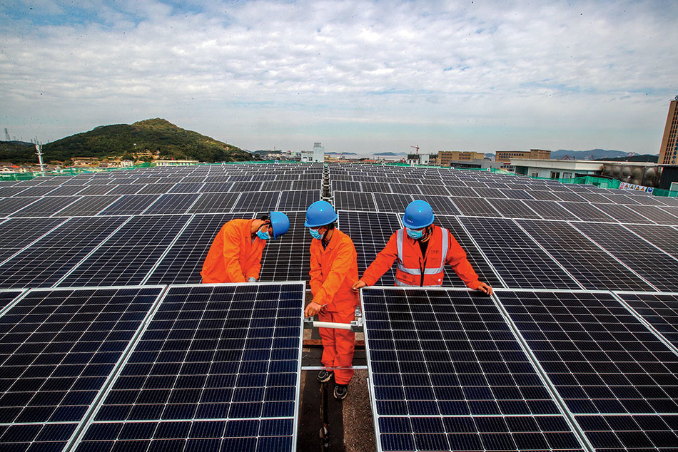 Workers installing solar panels on the roof of a fish-processing plant in Zhoushan, China