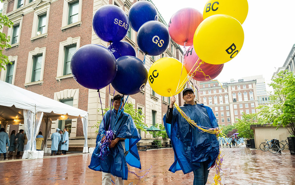 Attendees at Columbia University 2022 commencement holding balloons in rain