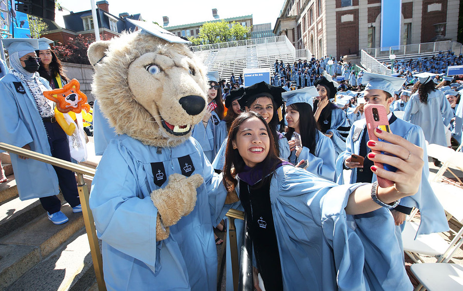 A Columbia graduate taking a selfie with Roar-ee at the 2022 Commencement ceremony