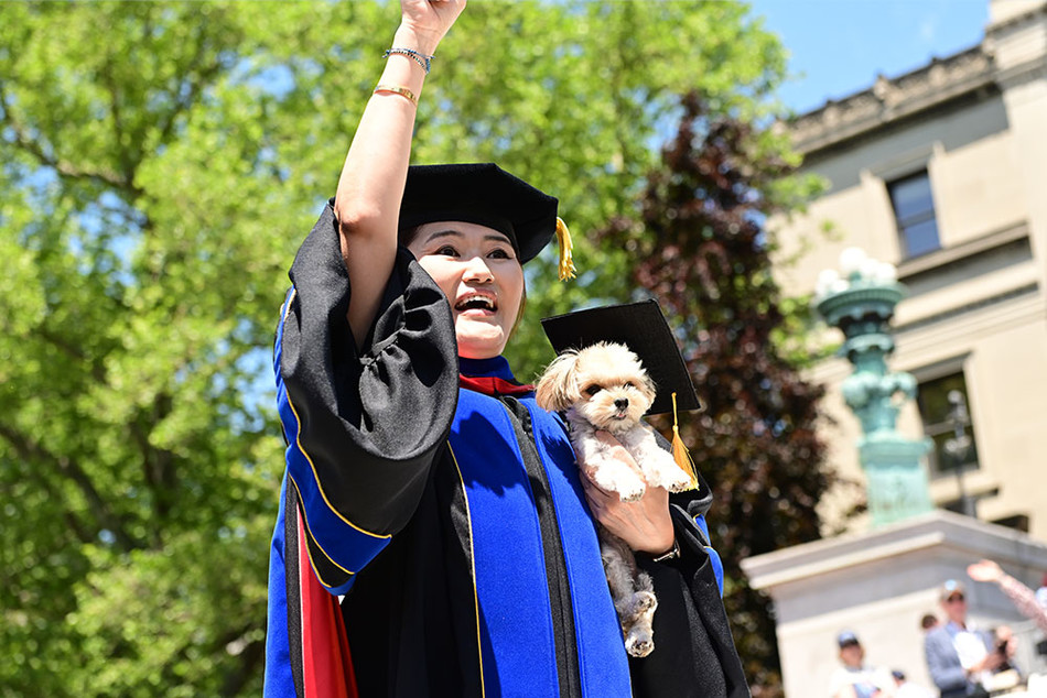 A woman holding a small dog at Columbia's 2023 commencement