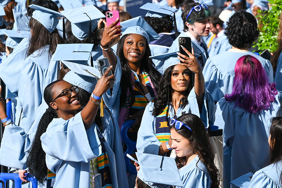 Columbia Business School graduates take selfies at 2023 Commencement