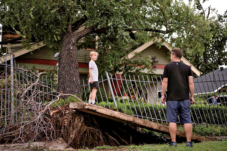 A father and son in front of a house after Hurricane Beryl