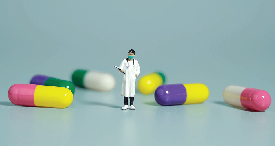 Graphic of a doctor figurine standing by giant pill capsules 