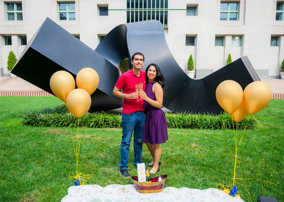 A couple gets engaged next to the Columbia University "Curl" statue