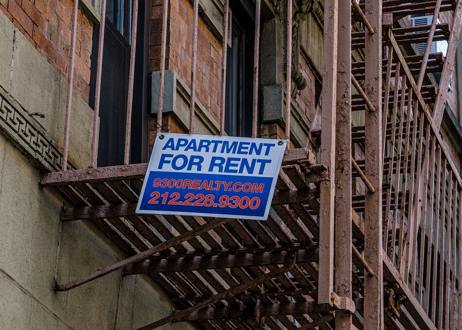 A New York City apartment building with a "for rent" sign