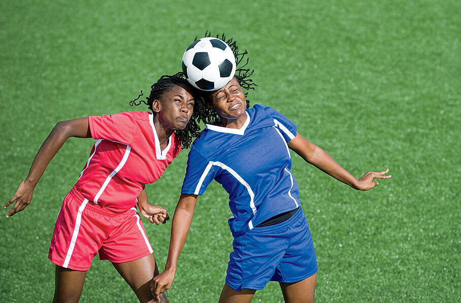 Two soccer players heading a ball