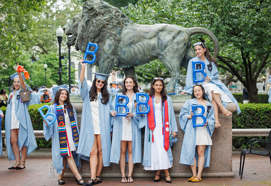 Columbia Business School graduates with the Columbia lion sculpture at 2026 commencement