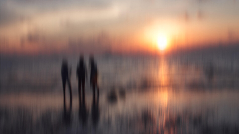 hazy photo of three figures on a beach